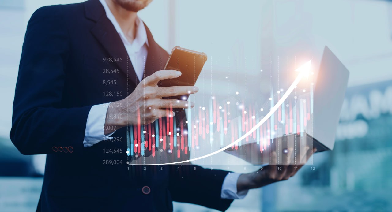 Trader monitoring rising market growth on phone and laptop